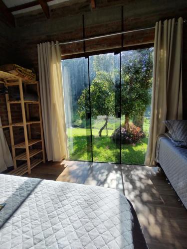 a bedroom with a large window with a view of a yard at Refúgio da Família Koch - casa de campo in Sinimbu