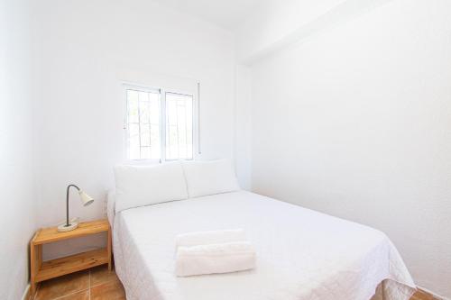 a small bedroom with a white bed and a window at Terraza del Mediterráneo - By Aloha Palma in Calabardina