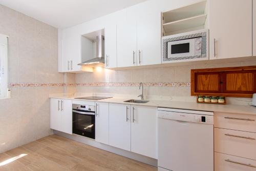 a kitchen with white cabinets and a microwave at Terraza del Mediterráneo - By Aloha Palma in Calabardina
