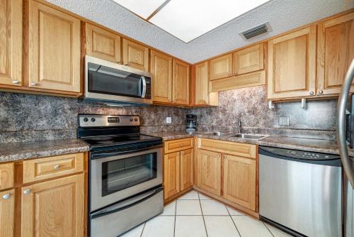 a kitchen with wooden cabinets and stainless steel appliances at Phoenix 2 Unit 2034 in Orange Beach