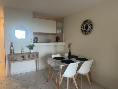 une salle à manger avec une table et des chaises blanches dans l'établissement Front mer magnifique appartement en rez-de-jardin, à Canet