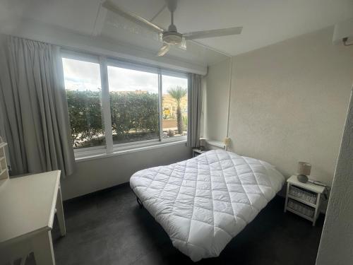 une chambre avec un lit blanc et une grande fenêtre dans l'établissement Front mer magnifique appartement en rez-de-jardin, à Canet