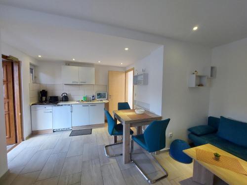 a kitchen and living room with a table and blue chairs at Ferienquartier T5 Bahnhofstraße 6 in Trassenheide