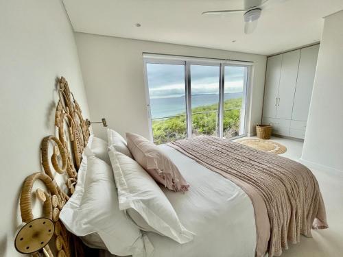 a bedroom with a bed and a large window at Fijnduin Beach House in Keurboomstrand