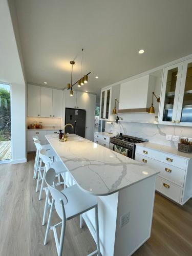 a kitchen with white cabinets and a marble counter top at Fijnduin Beach House in Keurboomstrand