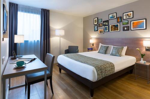 トゥールーズにあるシタディーン アパートホテル トゥールーズ ウィルソンのベッドとデスクが備わるホテルルームです。