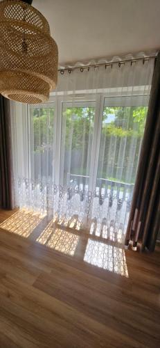 a room with a large window with curtains and a chandelier at Słoneczna kawalerka - studio in Gdańsk