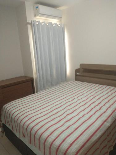 a bedroom with a bed with a striped blanket at Casa aconchegante in Feira de Santana