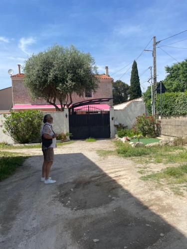 a woman standing in the driveway of a house at La Coccinelle in Nîmes