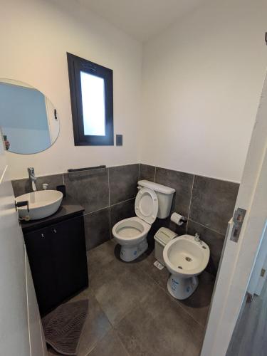 a bathroom with two toilets and a sink and a mirror at Cabaña Container en Viñedos in San Rafael