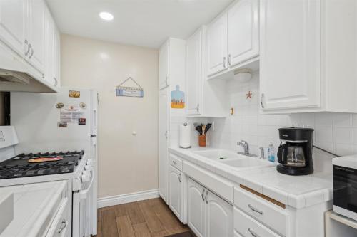 a white kitchen with a stove and a sink at Lovely 1 Bed Beach Condo #128 in Carpinteria