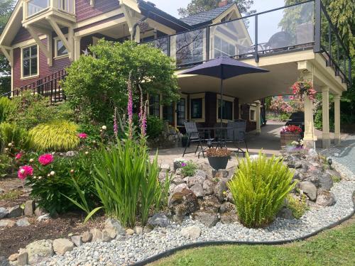 a house with a garden with flowers and an umbrella at Ladysmith Harbour View House in Ladysmith