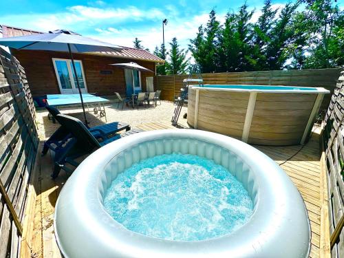 a large hot tub on a deck with a table and an umbrella at Les Appartement du Mas - RUBIS in Aigues-Mortes