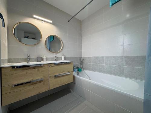 une salle de bain avec une baignoire, un lavabo et un miroir dans l'établissement Maison avec piscine, jardin et barbecue, à Craponne