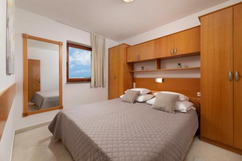 a bedroom with a large bed with a mirror at Apartments Kvarner 2 in Malinska