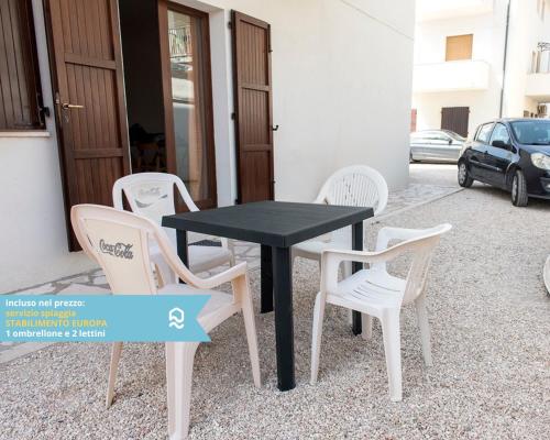 een zwarte tafel en witte stoelen voor een gebouw bij RS317 - Marcelli, bilocale in residence fronte mare in Marcelli