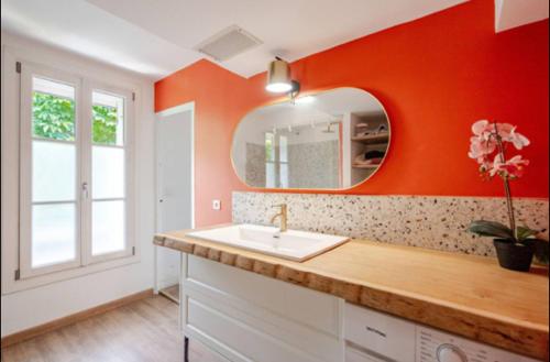 La salle de bains orange est pourvue d'un lavabo et d'un miroir. dans l'établissement Aix-en-Provence : appartement de charme centre ville, à Aix-en-Provence