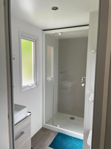 une salle de bain avec une douche en verre avec une fenêtre dans l'établissement Parenthèse nature au Cap Ferret, à Lège-Cap-Ferret
