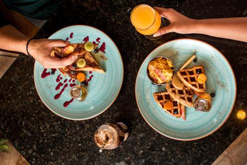 two plates of food on a table with people eating at Mantra Hotel Boutique in Santa Marta