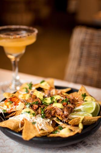 a plate of nachos on a table with a drink at Mantra Hotel Boutique in Santa Marta