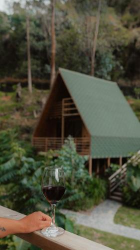 a glass of wine sitting on a table in front of a cabin at EcoHotel Cantos del Rio in Cajamarca
