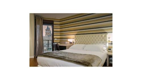 a bedroom with a bed and a desk with a window at U-Hotel Spa Ciudad de Astorga in Astorga