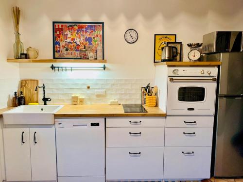 La cuisine est équipée de placards blancs et d'un four blanc. dans l'établissement La Maison des Pérolles, à Santenay