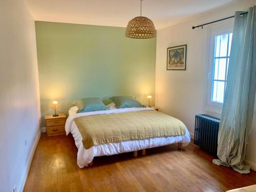 a bedroom with a large bed with blue pillows at La Maison des Pérolles in Santenay