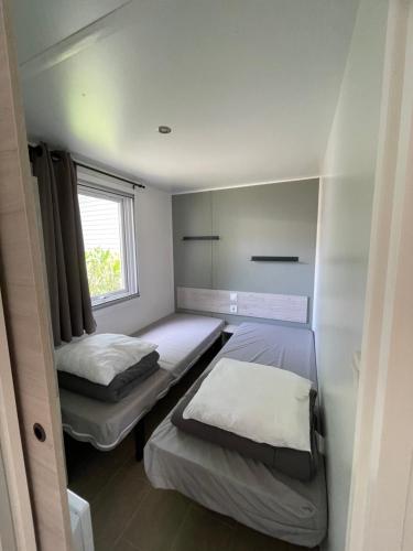 une petite chambre avec deux lits et une fenêtre dans l'établissement Parenthèse nature au Cap Ferret, à Lège-Cap-Ferret