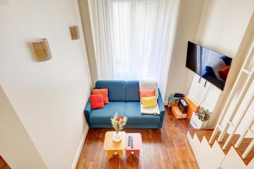 un salon avec un canapé bleu et une télévision dans l'établissement Coco meulin rouge, à Paris
