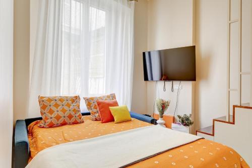 - une chambre avec un lit doté d'oreillers orange et une télévision dans l'établissement Coco meulin rouge, à Paris