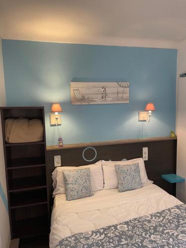 a bedroom with a bed with a blue wall at Hotel Clair Logis in Argelès-sur-Mer