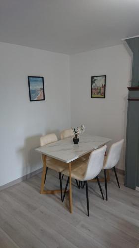 a dining room table with white chairs and a white wall at Cosy avec spa et sauna et jardin in Boulogne-sur-Mer