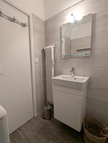 une salle de bain blanche avec un lavabo et un miroir dans l'établissement Appartement 5 personnes avec garage, balcon et belle vue, à Le Mont-Dore