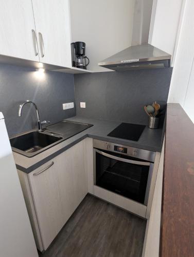 une petite cuisine avec un évier et une cuisinière dans l'établissement Appartement 5 personnes avec garage, balcon et belle vue, à Le Mont-Dore