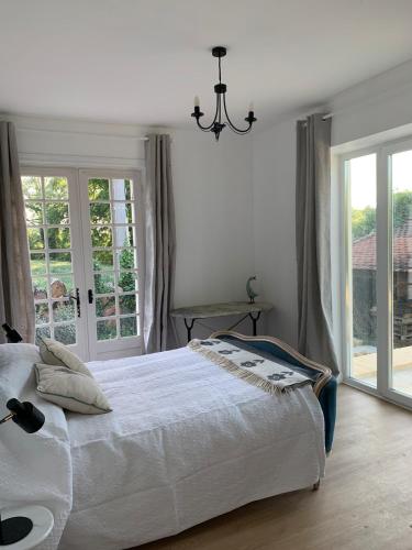 une chambre avec un grand lit blanc et des fenêtres dans l'établissement Riverside Retreat, à Badefols-sur-Dordogne