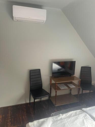 a room with two chairs and a table and a television at Turul Panzió&Pizzéria in Szólád