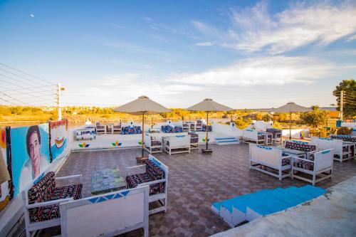 a patio with white tables and chairs and umbrellas at Nubian Kulih house in Aswan