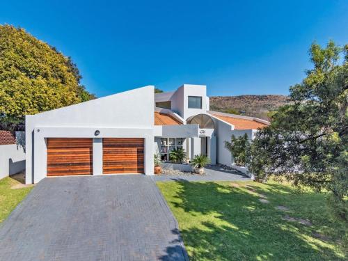 a large white house with a driveway at Mind-Body-Soul Guesthouse on Featherbrooke Estate, Krugersdorp, South Africa in Krugersdorp