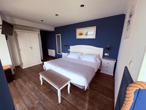 a bedroom with a white bed and blue walls at Posada Punta Liñera in San Vicente de la Barquera