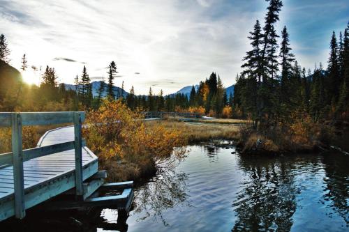 a bridge over a river with a boat in the water at Boardwalk Bliss - Top Floor Downtown Condo in Canmore