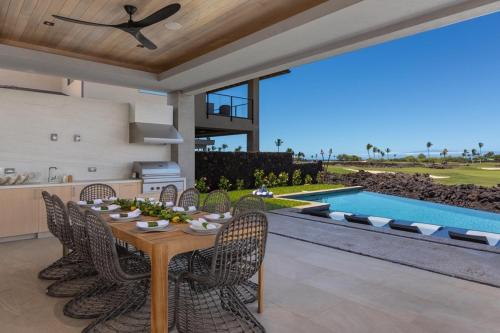 a dining room with a table and chairs and a pool at 5BD Mauna Lani Lux Golf Estate (4) at One Ocean in Waikoloa