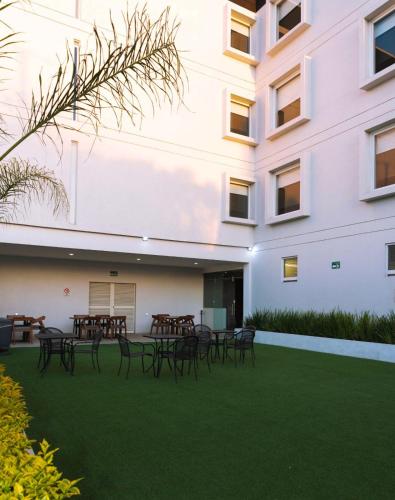 Un patio con mesas y sillas frente a un edificio. en Fato Hotel, en Querétaro