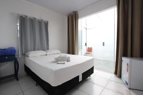 a bedroom with a bed and a large window at Wafeh Pampulha Suítes in Belo Horizonte