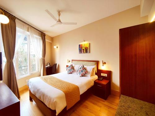 a bedroom with a large bed and a window at Dzongkar - MG Marg - 3 Star Hotel in Gangtok