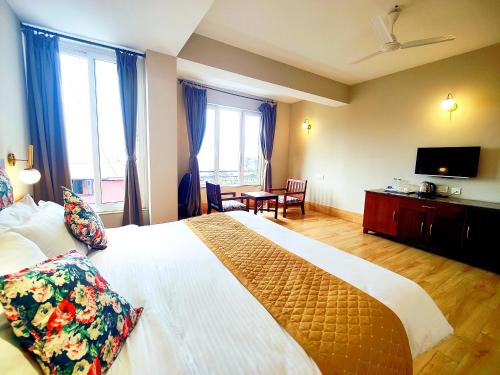 a bedroom with a large bed and a television at Dzongkar - MG Marg - 3 Star Hotel in Gangtok