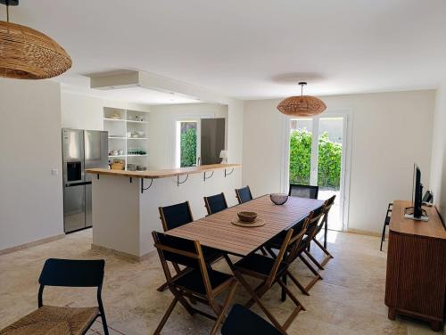 une cuisine et une salle à manger avec une table et des chaises en bois dans l'établissement Maison climatisée avec Grand Jardin - 10 min à pied du Brusc et de sa plage, à Six-Fours-les-Plages