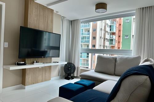 a living room with a tv and a couch and a window at T501 - Apto Novo Ar cond Cama Queen Vaga in Vitória