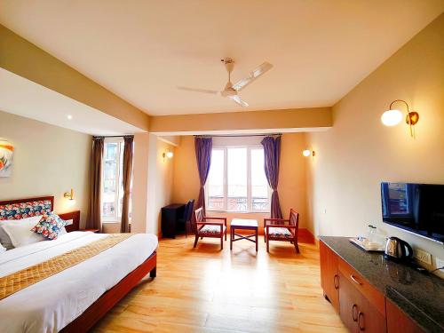 a hotel room with a bed and a television at Dzongkar - MG Marg - 3 Star Hotel in Gangtok
