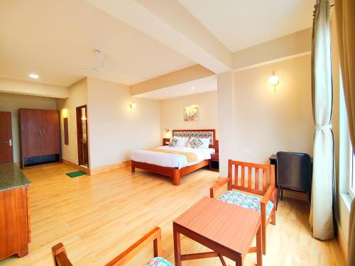 a bedroom with a bed and a table and chairs at Dzongkar - MG Marg - 3 Star Hotel in Gangtok